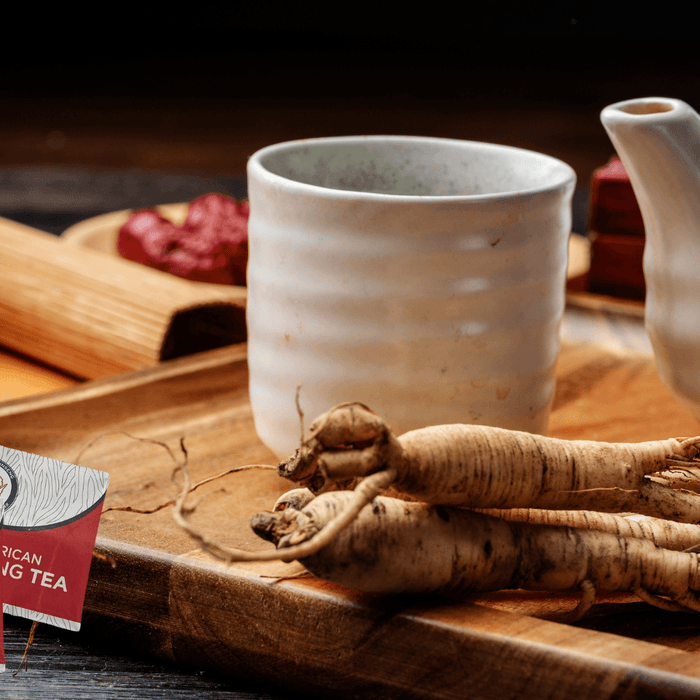 Wisconsin ginseng tea bags with whole American ginseng roots, ceramic cup, and teapot on wooden tray